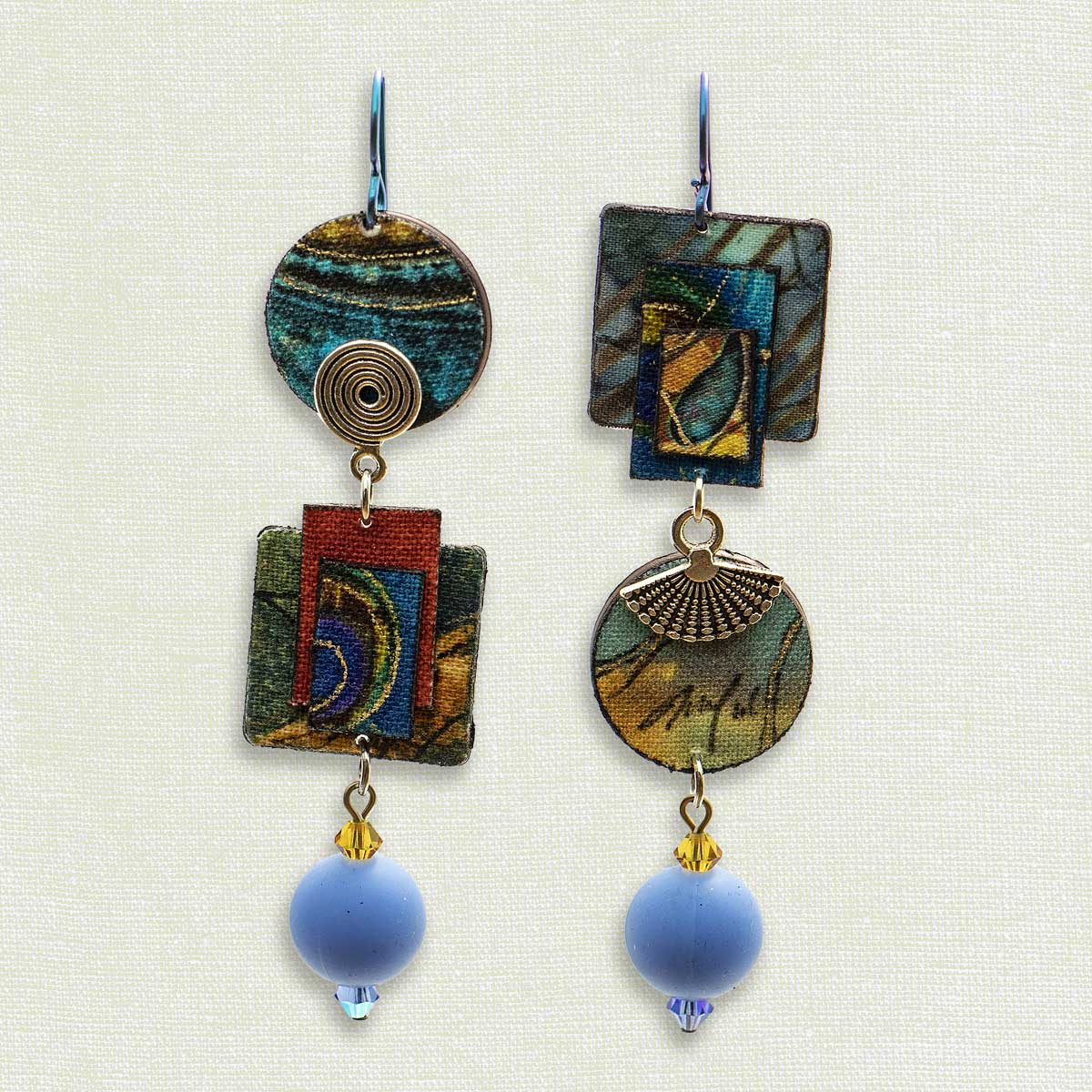 Asymmetric 3 tiered earrings, hand painted by artist Suzanne Bellows for SuzanneBellowsJewelry.com. This pair is part of the Earth Collection and features vibrant blues, greens and red.